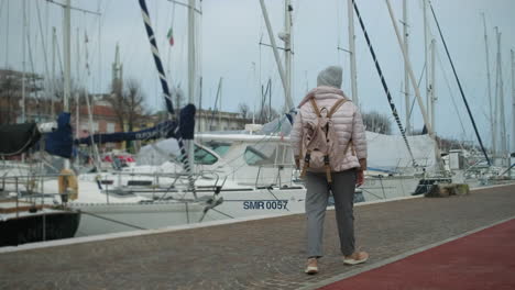 woman walking along a pier with boats