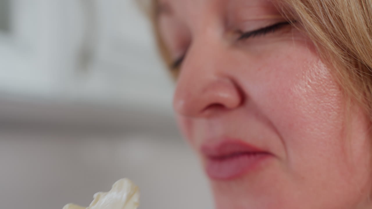 손가락에 크림 버터를 들고 코에 가까이 가져오고 현대 주방에서 만족스러운 표정으로 향기를 인식하는 사람의 클로즈업 손 시각