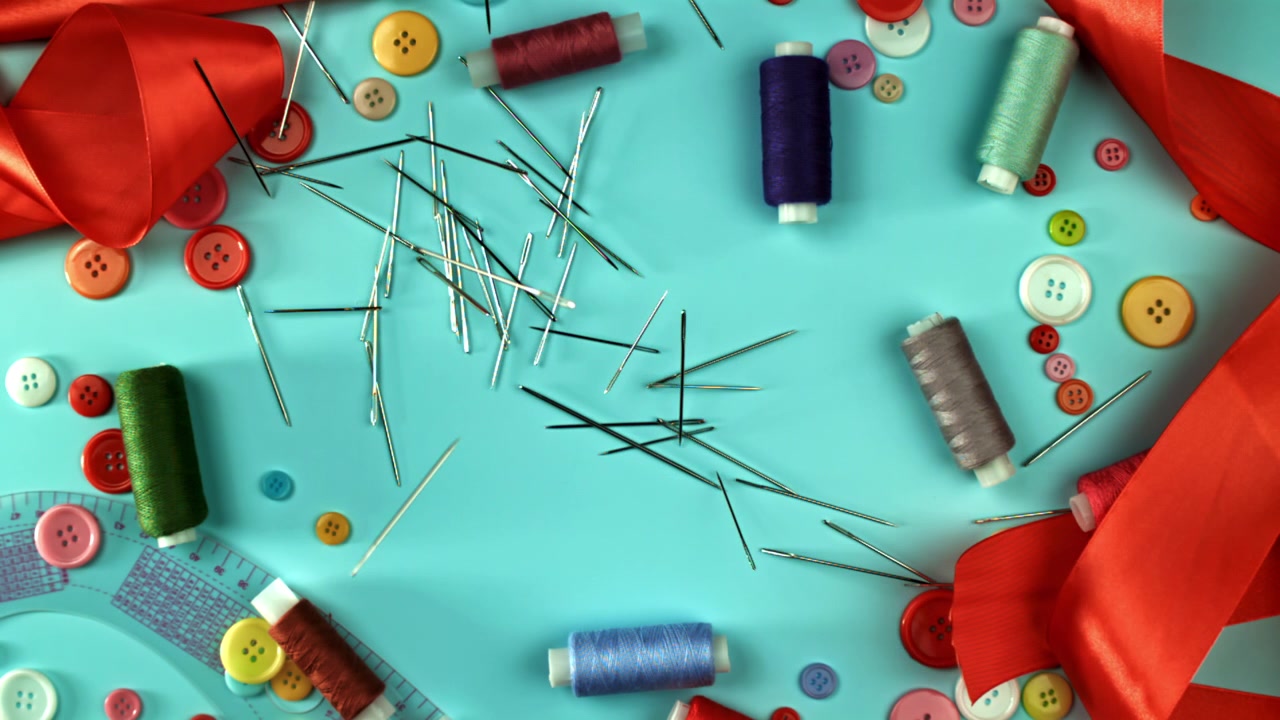Sewing Needles Falling and Scattering on a Blue Background with Craft Supplies