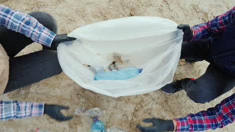 Voluntarios-Ponen-Basura-Plástica-En-Una-Bolsa-Limpiando-La-Playa-Cuidando-El-Medio-Ambiente