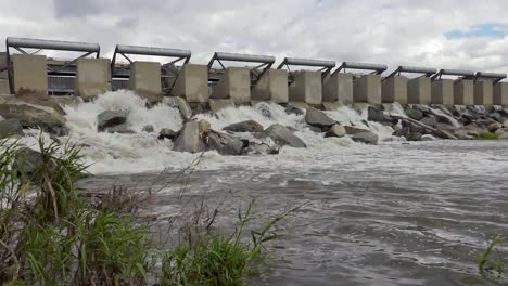 Left-to-right-pan-of-concrete-dam-gate-with-rushing-water