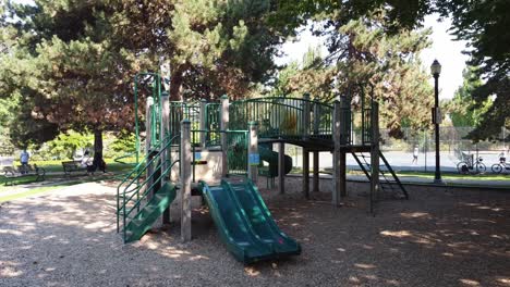 aerial-hold-side-view-of-an-empty-deserted-childrens-playground-and-people-walking-playing-tennis-during-social-distancing-COVID-19-bylaws-lockdown-next-to-a-vintage-victorian-light-post-and-bench