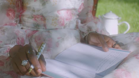 black lady in summer dress finished writing in diary - picnic in park, close up