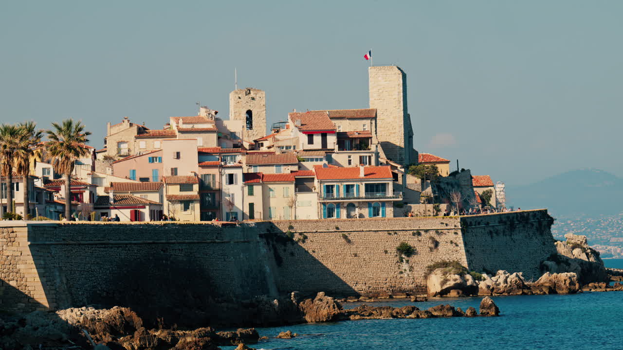 Distant view of people walking on the coast of Antibes, France