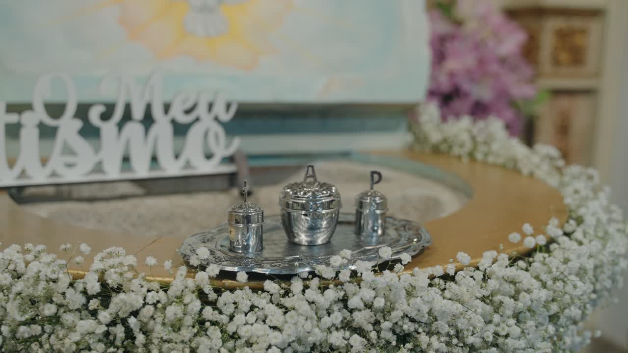 close up of silver christening vessels surrounded by delicate white flowers