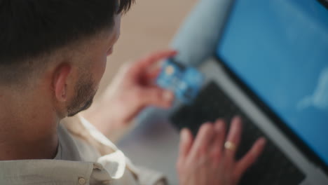 hombre comprando en línea con tarjeta de crédito y portátil