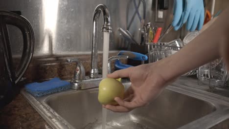 cleaning the small golden apple in the kitchen sink