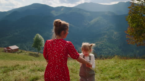 joyful woman jumping daughter enjoying family leisure on meadow. summer vacation