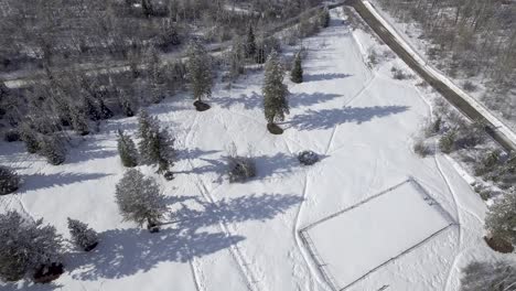 aerial-flying-over-snowy-horse-pasture-in-rural-landscape