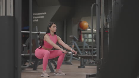 a young woman squats in a crossover to train her thigh and leg muscles. buttocks training. professional female athlete does leg exercises squats