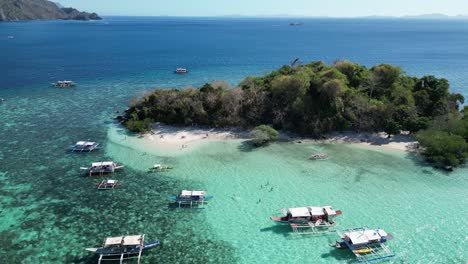 drone reveal tour boats in clear blue water of tropical cyc island reef in coron