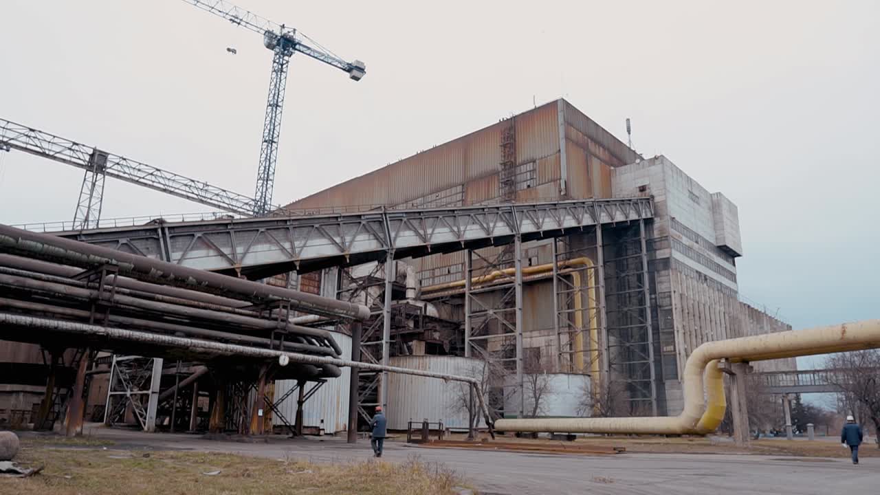 Old coal-fired power plant with metal structures, pipes and construction cranes. Industrial area of the plant