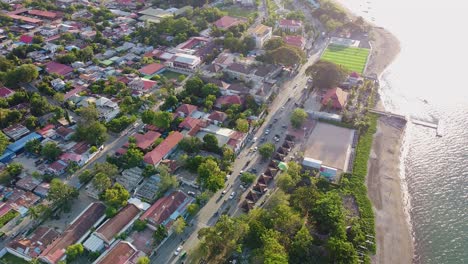 Frei-Fließender-Verkehr,-Der-Sich-Auf-Der-Hauptstraße-Am-Wasser-In-Der-Hauptstadt-Dili,-Timor-Leste,-Bewegt,-Luftdrohnenansicht-Mit-Blick-Auf-Das-Meer-Auf-Der-Tropischen-Insel-Osttimors