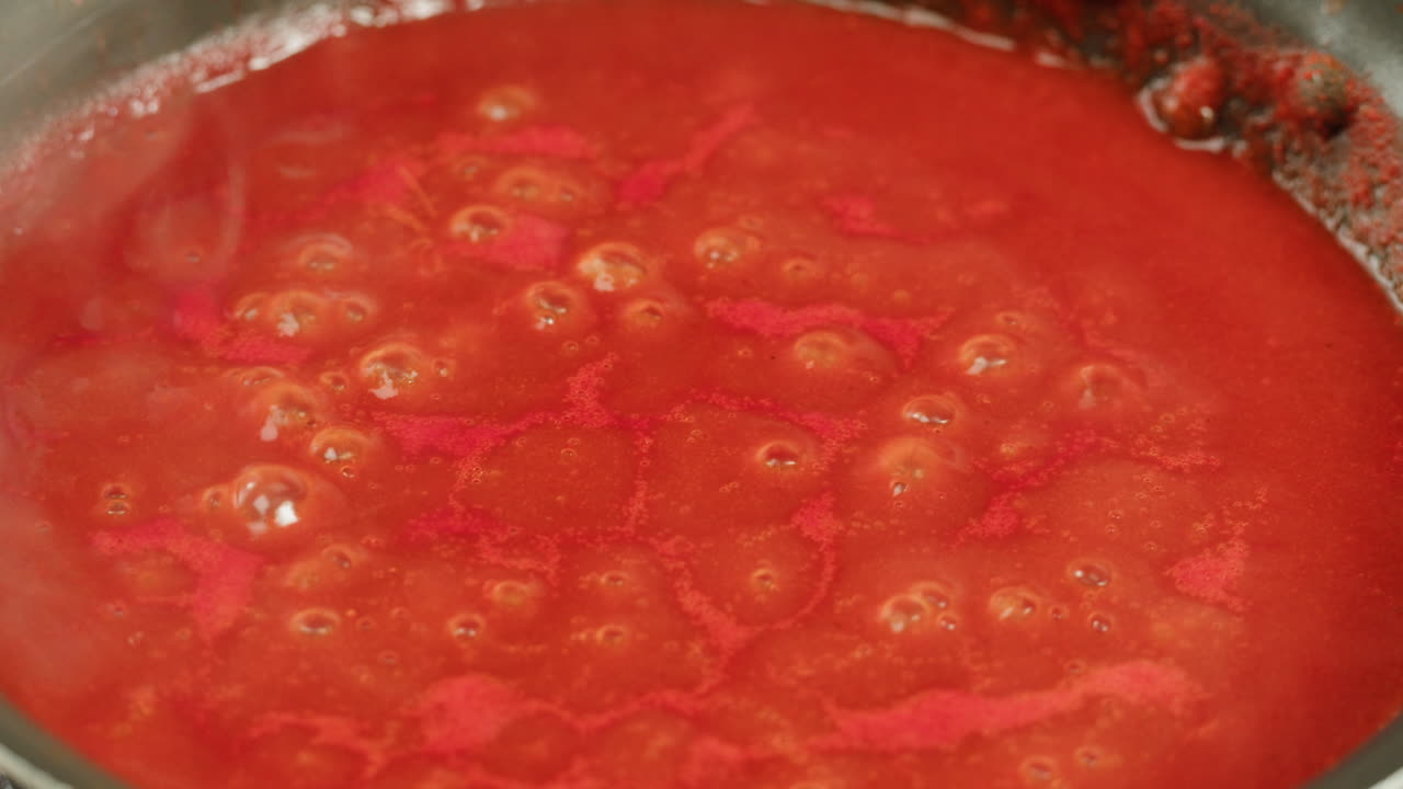 Chicken in tomato sauce is boiling on a frying pan with spices. Cooking tomato sauce curry with chicken fillet. Traditional Italian Mexican Asian dish. High quality studio shot for cafe, restaurant close up.