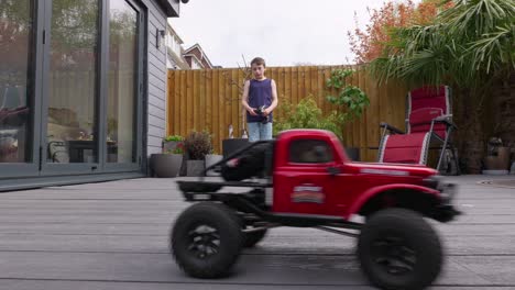 young boy at home outdoors in the garden playing with his rc car, truck, 4 x 4