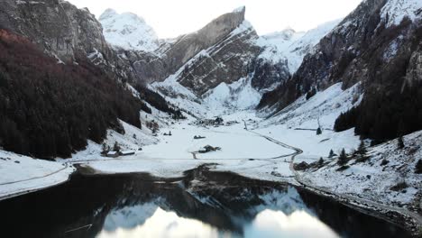 aerial flyover from side to side above seealpsee in appenzell, switzerland in winter with snow and reflection on the lake - 4k