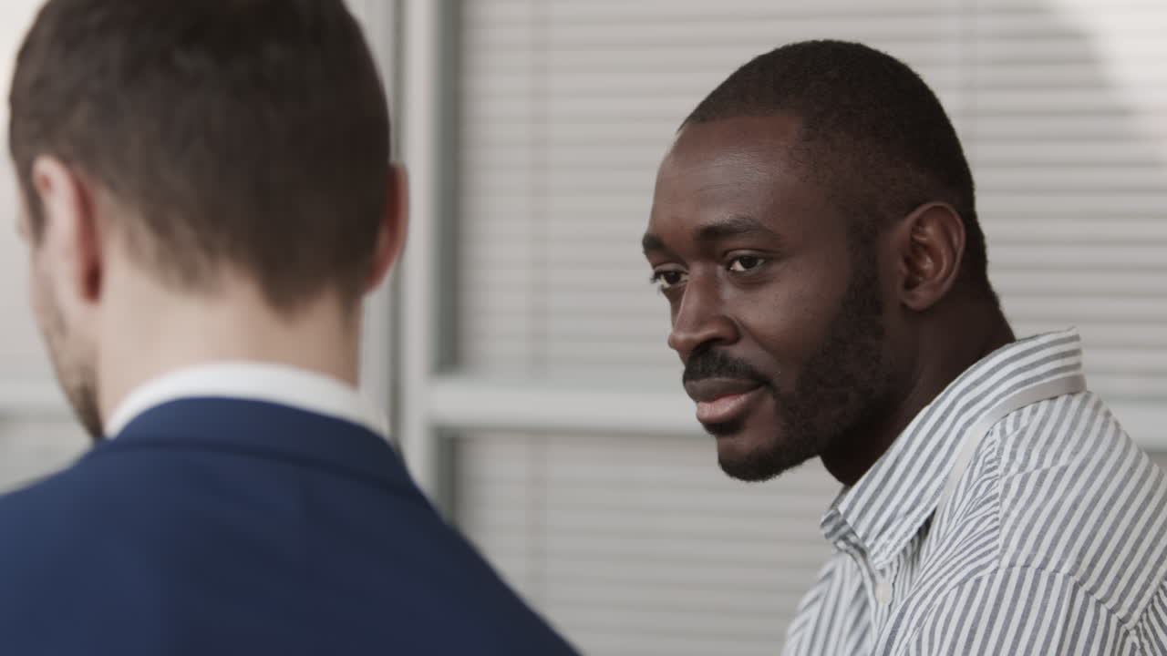 African Man Talking to Unrecognizable Colleague