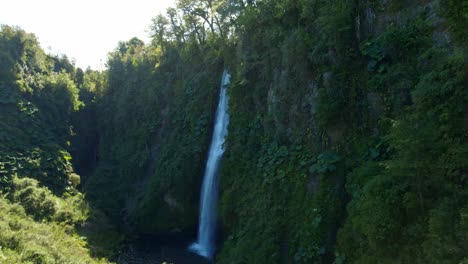 aerial drone rises above waterfall landscape around green cliff in chiloé chile patagonian summer