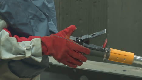 empleado en uniforme y guantes sostiene el cepillo de aire en el taller