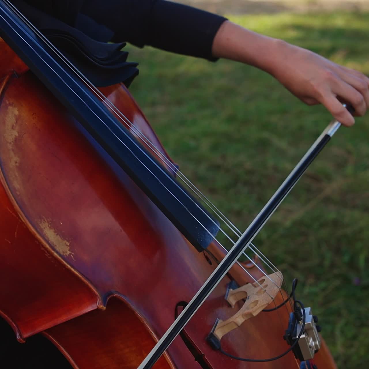 Pretty woman playing on nature landscapes. Musical perfomance of playing cello