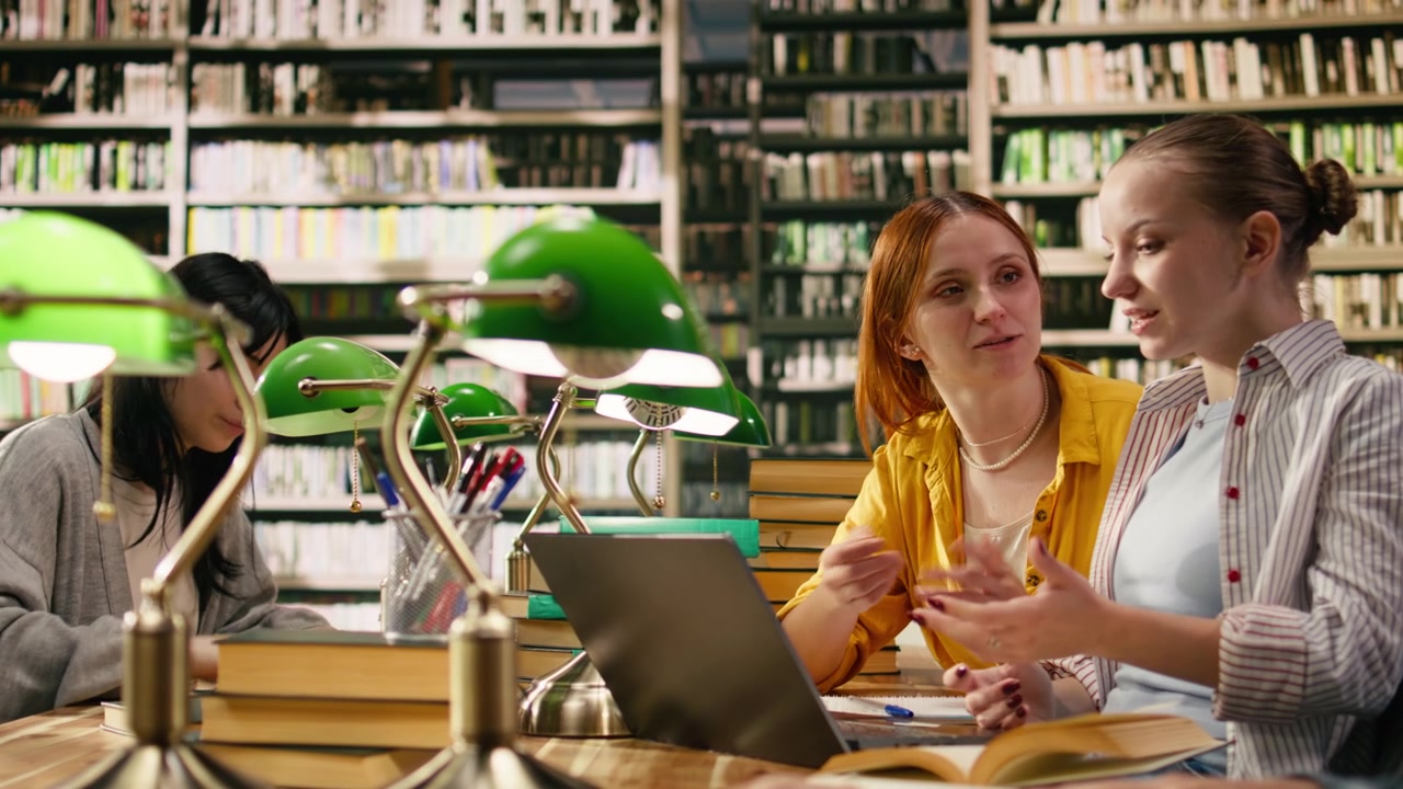 Mentore che guida uno studente nel lavoro accademico al laptop in biblioteca