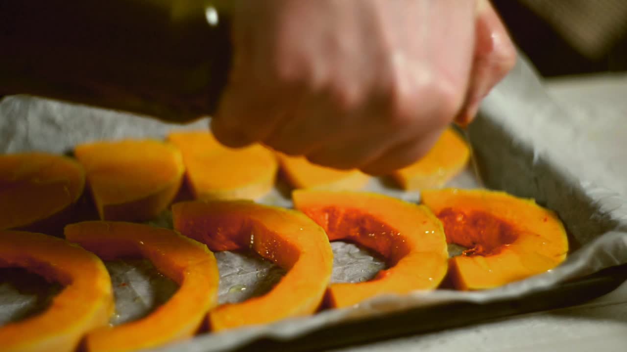 trozos de calabaza vertiendo aceite de oliva. verduras horneadas cocinando. plato de calabaza