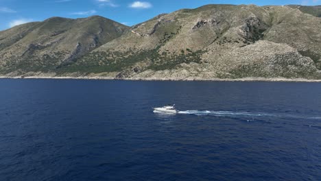 yacht cruising in the sea along the mountain range in shpella, albania. - aerial shot