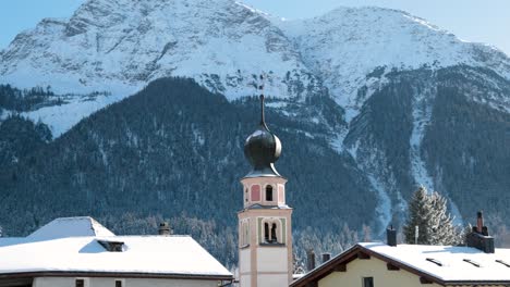 traditional church and houses in a swiss village with mountains in the background in switzerland