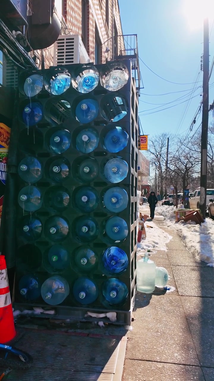 New York, USA, 9. Januar 2025: Wasserflaschen vor New Yorker Geschäft gestapelt. Große Wasserflaschen auf dem Bürgersteig vor einem kleinen New Yorker Laden im Winter gestapelt