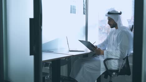 handsome man with traditional clothes working in an office of dubai