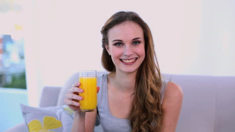 happy model drinking orange juice on the couch