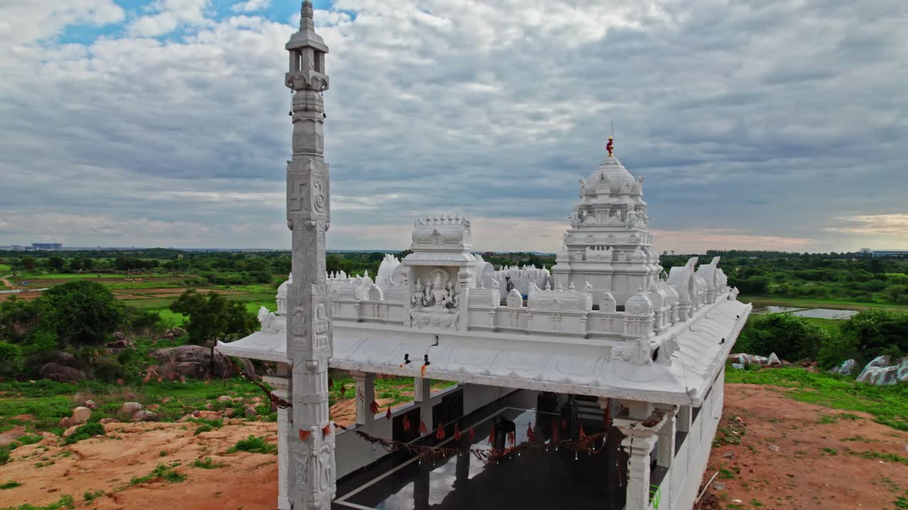Temple with Dhwaja Stambha and agricultural land at day time, overtake shot or push in shot, drone shot, 4k.