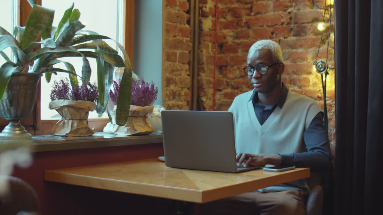 Black Man Drinking Coffee and Using Laptop in Cafe