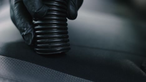 primer plano de un hombre con guantes negros aspirar un coche interior negro