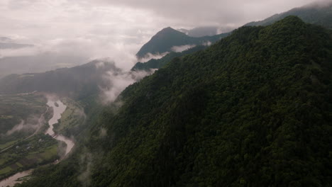 Tilt-up-aerial-shot-revealing-massive-rainy-overcast-covering-mountain-summits