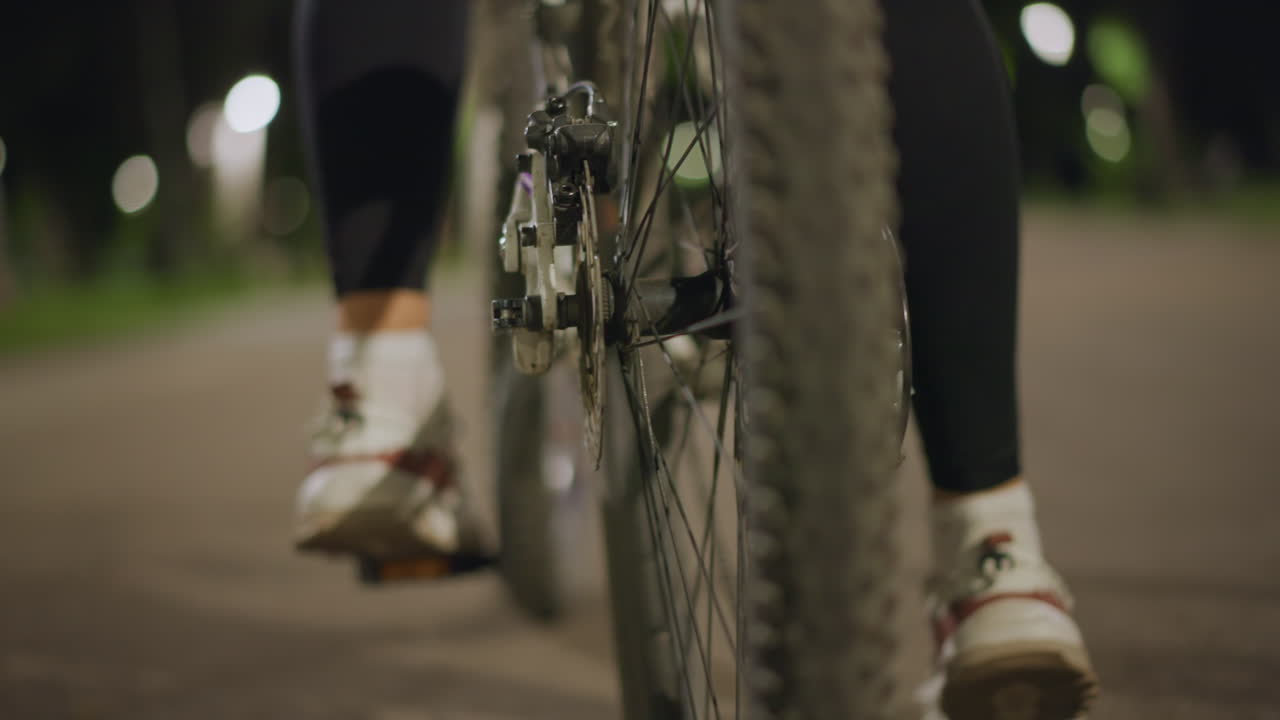 Bike Parts Illuminated, Pedal And Wheel In Focus, Nighttime Shot Of Bicycle Gear Movement, Detailed Image Capturing Bicycle Pedal Crank And Wheel Rotating On Park Pavement At Night