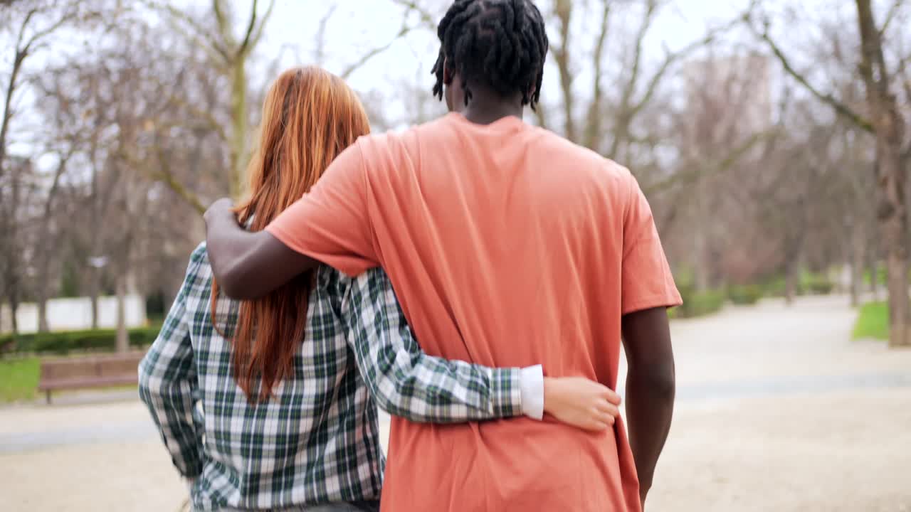 A couple walking in a park with their arms around each other