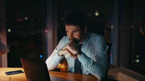 worried manager sitting night workplace looking laptop close up. worker tired