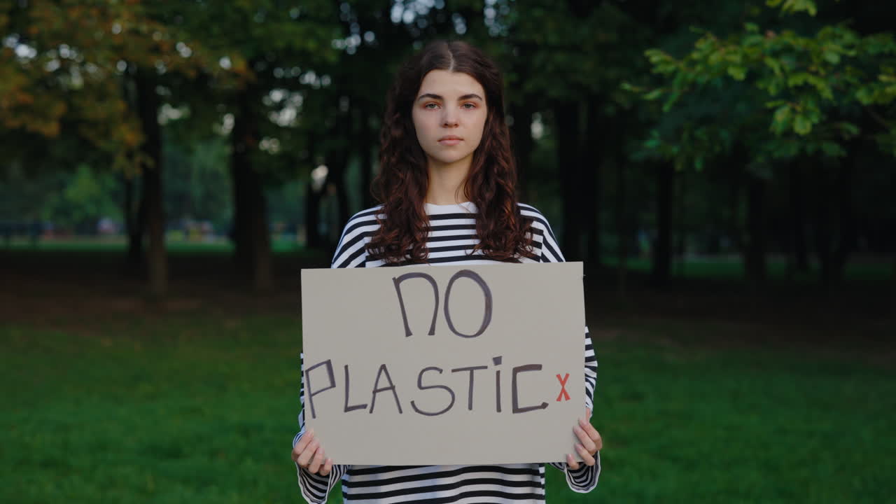 Young Woman Holding No Plastic Sign in Park