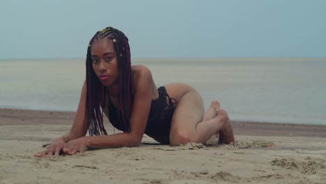 a young girl in a bikini laying in the sand along a tropical caribbean shore.