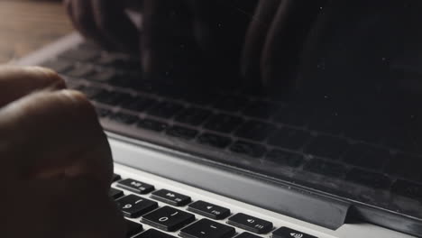 escritura a mano en el teclado de la computadora portátil con el reflejo reflejado en la pantalla