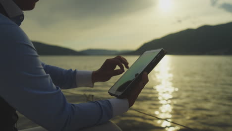 person using a tablet on a boat at sunset