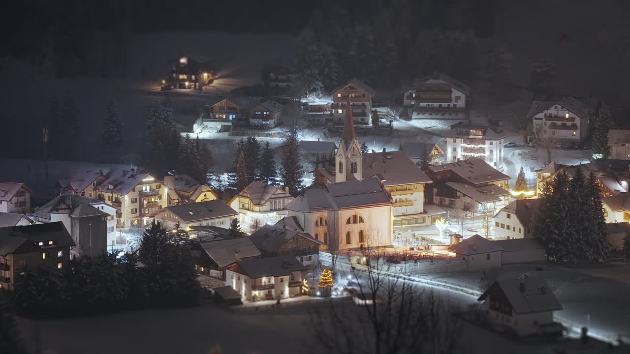 An alpine village of San Vigilio in the Italian Dolomites covered with snow and illuminated by street lights. Til-shift video.