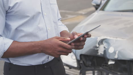 primer plano de un ajustador de pérdidas de seguros con una tableta digital inspeccionando el daño al coche por un accidente automovilístico