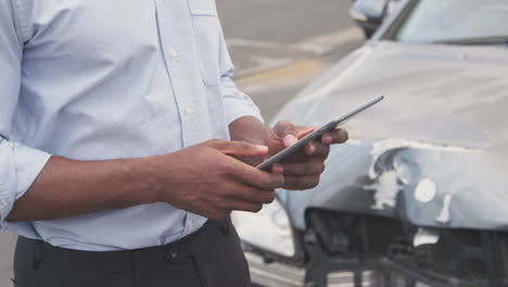 close up of insurance loss adjuster with digital tablet inspecting damage to car from motor accident