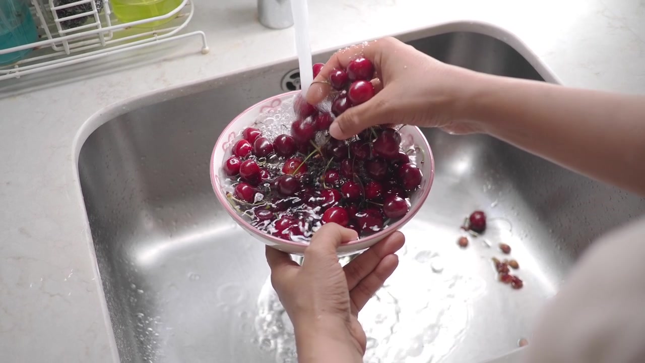 Person Washing Fresh Red Cherries in a Kitchen Sink