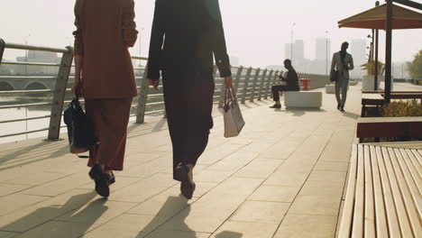 business people walking on embankment in city on summer day