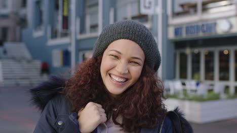 portrait of happy mixed race woman with frizzy hair laughing cheerful wearing fur coat beanie hat in urban background