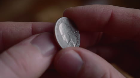 dedos lanzando una moneda de un cuarto de dólar en la mano
