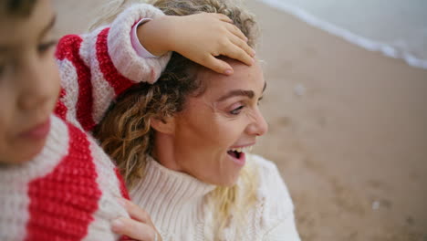 closeup mother hugging child at ocean shore. smiling woman looking kid with love